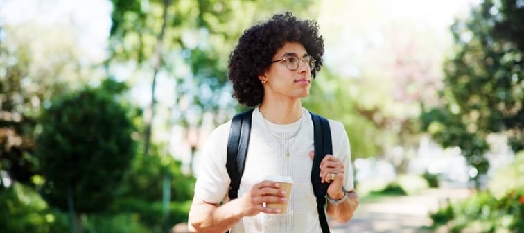 man on campus with coffee, backpack and glasses on morning commute to college