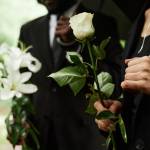 Close up of people holding roses at a funeral