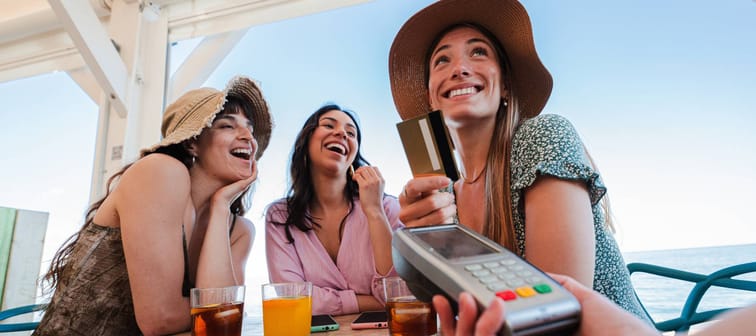 Happy young women paying for meal using debit card