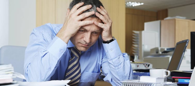 Frustrated middle aged businessman sitting at office desk