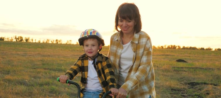 Mom holding son steady on a bike